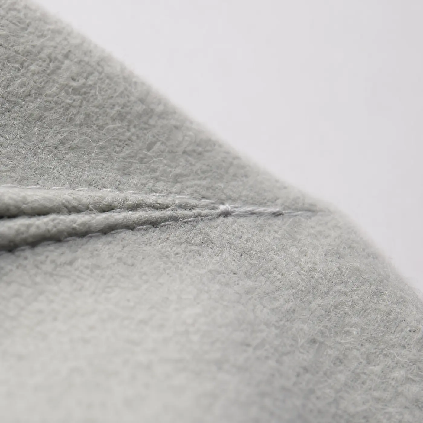 The point of a sewn dart running out to nothing on pale wool.