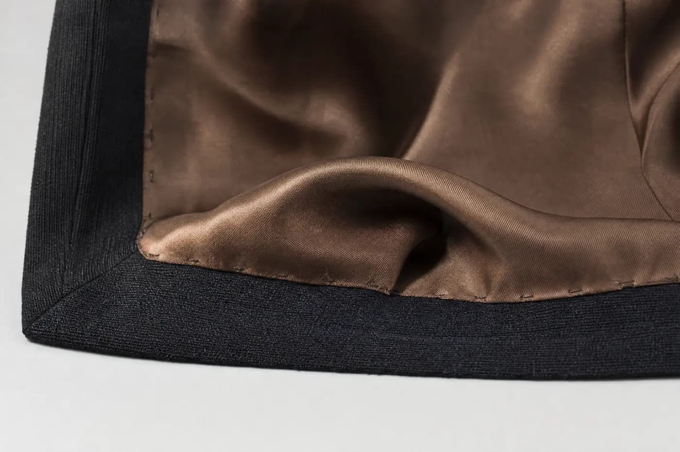 A lining attached at a hem with a deliberate horizontal fold of slack.