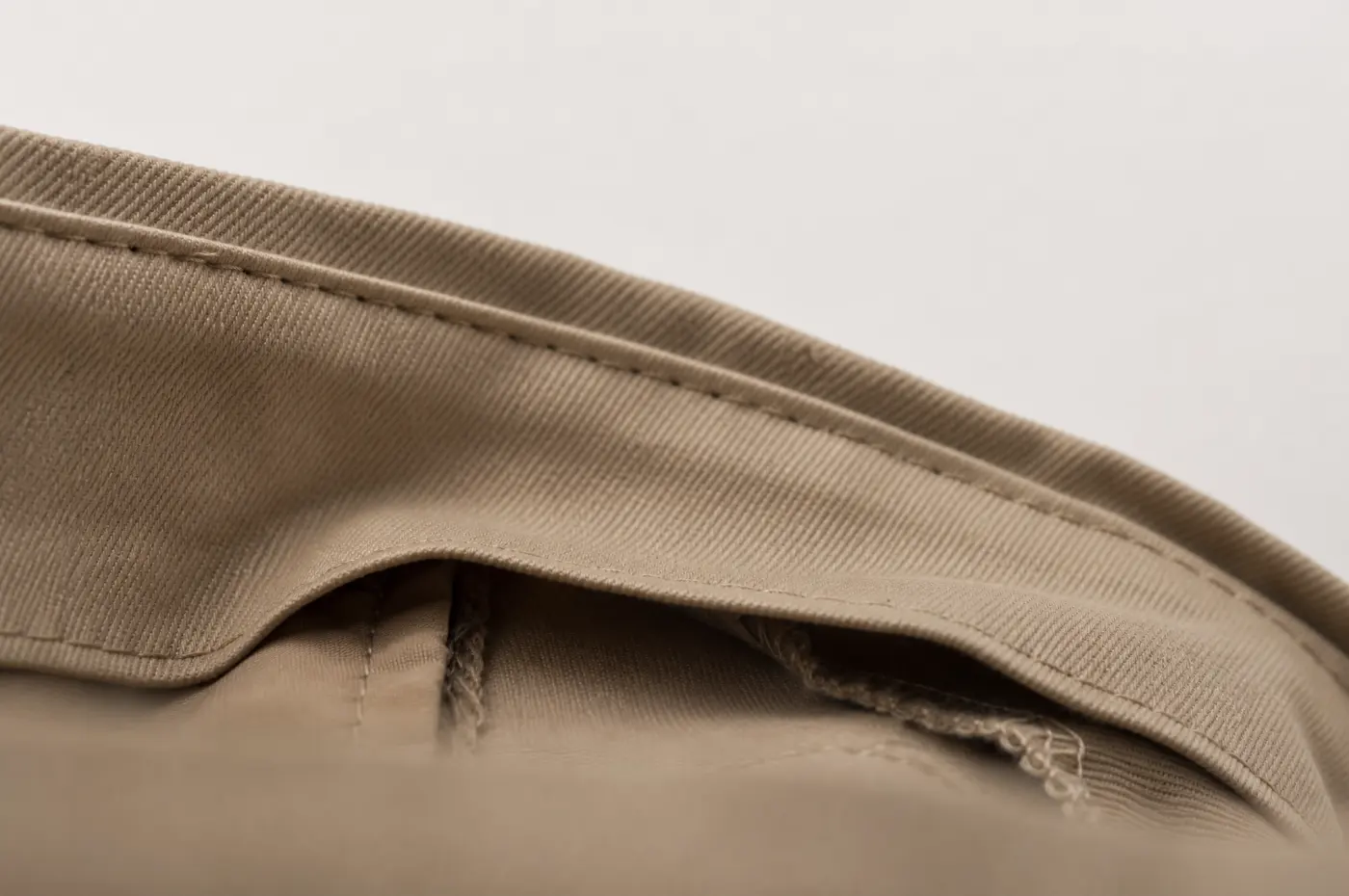 The inside of a trouser waistband showing an inner facing layer.