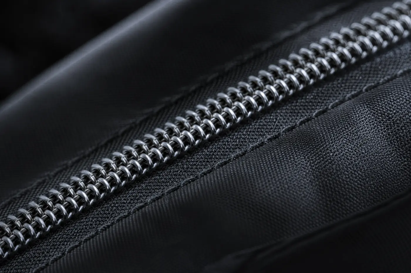 A zip set into dark fabric with stitching running beside the teeth.